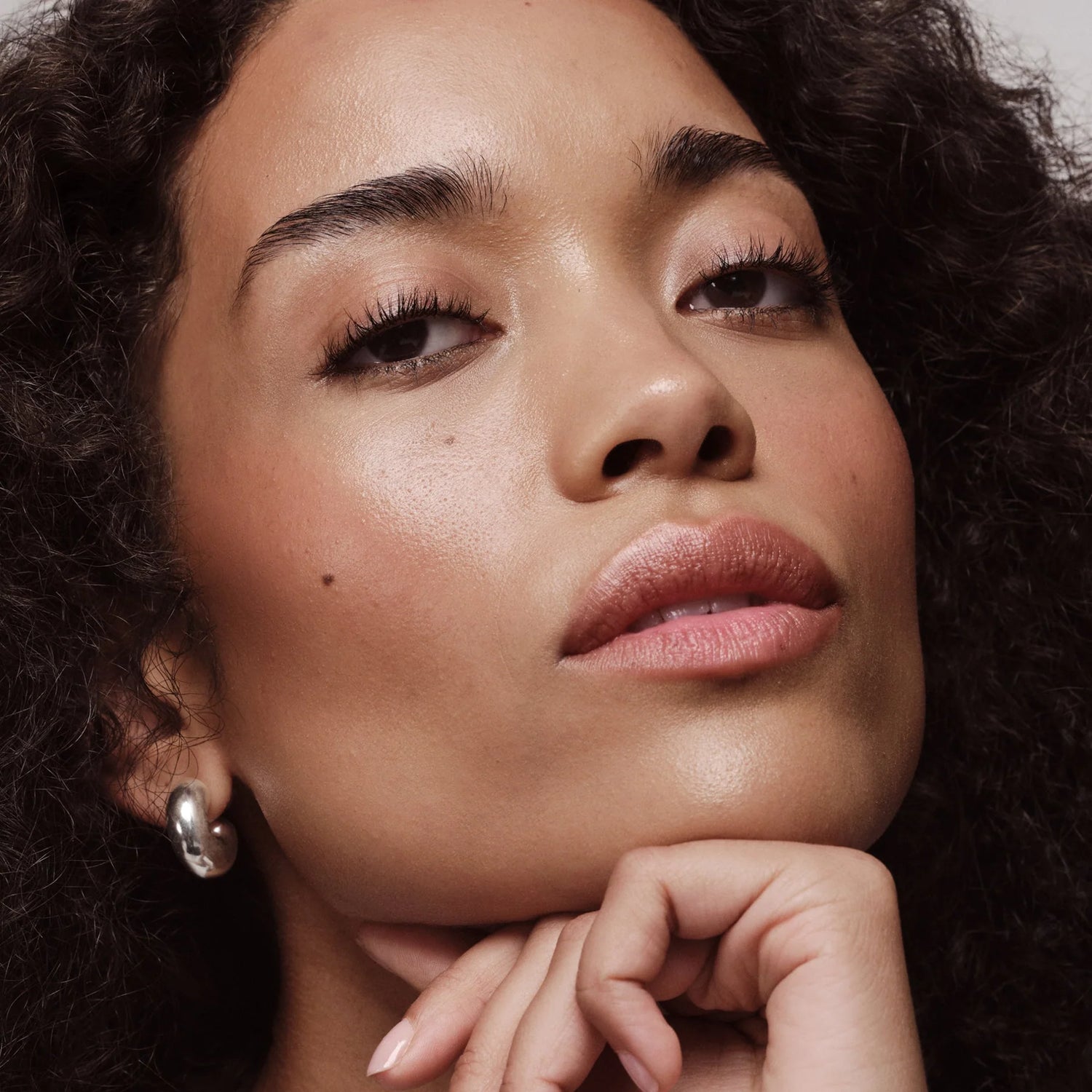 Close-up of a woman with curly hair and a neutral expression.