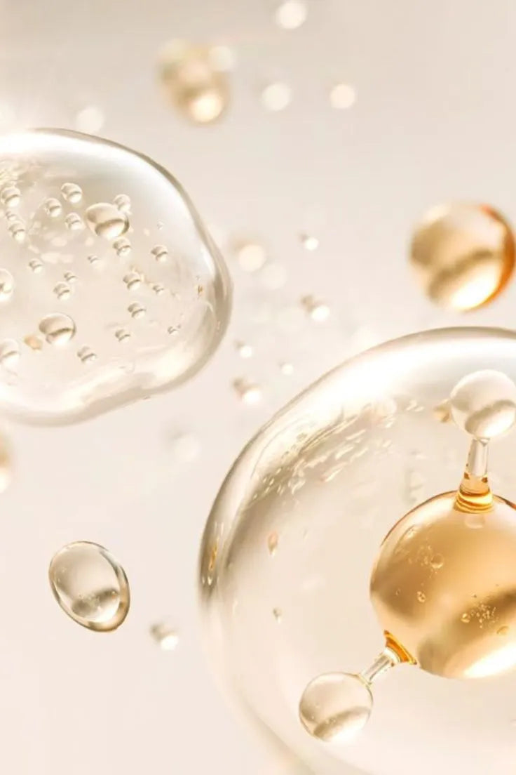 Close-up of gold droplets and bubbles on a light background